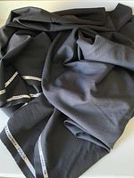Photo showing the black fabric draped to display texture and selvage text.
