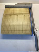 Full view of vintage Quartet paper cutter from above, showing cutting arm and grid marked base surface in metric and imperial units.