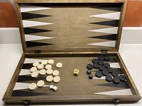 Open wooden backgammon board showing playing pieces, dice and doubling cube inside.