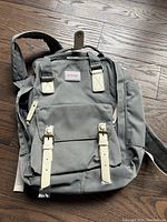 Gray Crocs backpack with front straps and brand label on wooden floor