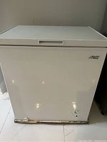 Front view of white closed Arctic King chest freezer with some rust or wear marks on the base.