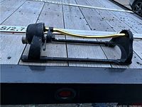 Oscillating garden sprinkler photographed on wooden surface showing entire sprinkler from side view.