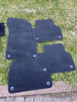 Four black floor mats arranged on grass, showing front and rear mats for Mercedes-Benz GLC300 SUV with mounting holes visible.