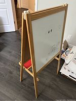 Side view of the double-sided easel art board showing the white dry-erase surface with some drawings on it.