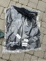 Photo of new black Mercedes Benz AMG floor mats wrapped in clear plastic packaging, showing labels and AMG logo.