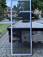 Full view of the screen door showing white metal frame and black mesh.