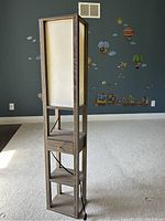 Full view of the wooden floor standing lamp with fabric shade, drawer, and two shelves. Shows electrical cord and overall condition.