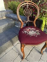 Full view of the antique chair showing carved backrest and floral tapestry seat.