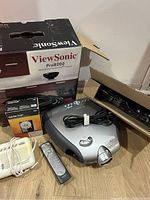 ViewSonic Pro8200 projector box, Sharp projector, white clock/timer device, remote control, power cords