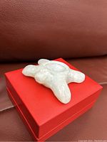 Top and side view of small soapstone turtle carving missing shell on a red box, showing texture and size.