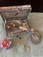 Overview of lot with jewelry box open displaying several jewelry pieces including bracelet, rings, giraffe holder, pendants, and earrings. Additional jewelry pieces arranged outside the box.