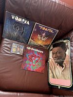 Photo of five music items on brown leather surface, including two Tomita LPs, Nat King Cole double LP, Chesdiscotheque LP and Michael Jackson CD.