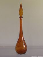 Full view of the tall vintage amber hobnail decanter showing its shape and texture.