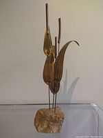 Full view of vintage metal sculpture depicting stylized bullrushes in copper and brass, mounted on a natural stone base, approximately 21 inches tall.