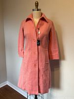 Full view of small pink wool coat on dress form, showing front button closure and collar.