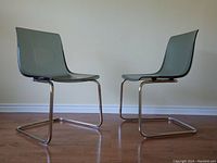 Side profile of two Tobias chairs showing chrome steel frames and smoked acrylic seats and backs placed opposite each other