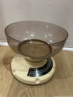 Top angle view of the Cosmo plastic kitchen scale with brown plastic bowl on cream base with visible scale dial.