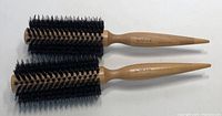 Two round WEN by Chaz Dean hair brushes with wooden handles and black bristles