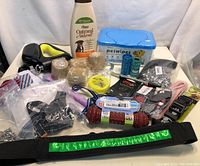 Full view of the dog supplies lot showing leash, grooming conditioner, chew toy, harnesses, waste bags and grooming accessories.