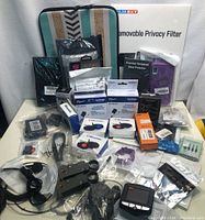 Original overview photo showing privacy filter, phone cases, multiple ink cartridges, chargers, and cables.