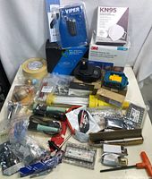 Full overview of lot items arranged on table showing masks, tools, tape, goggles, and various hardware parts.