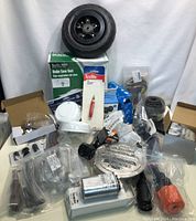 Lot showing assorted industrial and hardware items including pneumatic wheel, vents, capacitor, wiring, and multiple packaged components