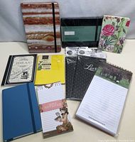 Photo showing all 9 notebooks and notepads in lot, various sizes and styles visible