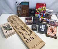 Lot showing wooden cribbage board and various playing card decks staged on white cloth background.