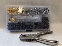 Photo showing the full set including the organized rivets in compartments and the rivet punch tool in front.