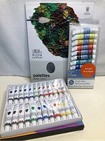 Set of Winsor & Newton paint palette sheet behind acrylic paint tubes from both sets