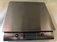 Image of a new digital food weighing scale with stainless steel top, digital display and control buttons.