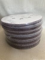 Side view of tightly stacked round sanding discs wrapped in plastic.