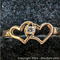 Clear view of the double heart design with the central diamond on the 10K yellow gold ring, showing detailed shape and gemstone.