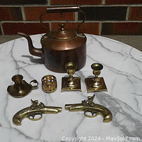 Overall view of the lot on marble surface showing the two muskets, four candle holders, and the coffee pot