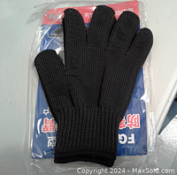 Pair of black knit cut resistant gloves displayed on packaging with some text beneath.