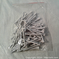 Clear plastic bag containing 50 white golf tees approximately 2 inches in length.