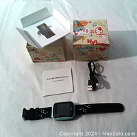 Kids GPS Watch Phone with black and teal silicone wrist strap, USB charging cable, instruction manual, and colorful packaging box.