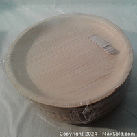 Stack of 10 inch round palm leaf plates sealed in original plastic shrink-wrap highlighting natural texture and condition.