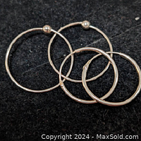 Photo showing both pairs of sterling silver hoop earrings on a black background, highlighting the difference in size and clasp type.