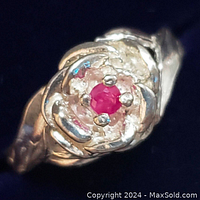 Close-up photo showing the sterling silver ring with rose petal design and central red ruby gemstone