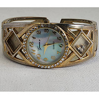 Front view of the watch showing mother of pearl dial with gold-tone Arabic numerals and rhinestone bezel.