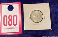 Photo showing a 1967 Canadian silver quarter in protective holder, next to a labeled card with '080'.