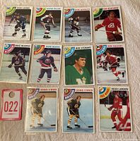 The complete lot of 11 hockey cards laid out on a flat surface, showing players from multiple NHL teams such as Canucks, Rangers, Flyers, Flames, Kings, Islanders, North Stars, Bruins, and Red Wings.