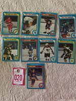 Top view of ten 1979-80 Topps hockey cards laid on a white fabric surface with a small numbered tag '020' included for reference. Cards represent various NHL teams and players.