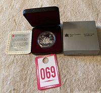 Photo of the 1989 Canadian silver dollar coin in original burgundy presentation case, silver Royal Canadian Mint box, and certificate of authenticity.