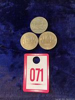 Three Canadian dollar coins shown on a dark blue fabric background; includes two coins with voyager ship design and one with Confederation Constitution design.