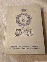 Front cover showing beige cloth hardcover with purple embossed text and emblem, mentioning support for Princess Elizabeth of York Hospital for Children