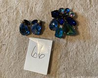 Full view of the clip earrings and brooch on a fabric background showing size and general condition.