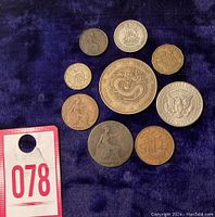 Coins arranged on a dark blue cloth showing all nine coins and auction number card 078.