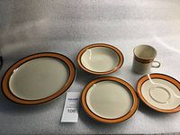 Oval serving platter, deep and shallow bowls, mug and saucer front view